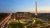 Aerial, exterior view of the National Museum of African American History and Culture at dusk with the Washington Monument in the background.